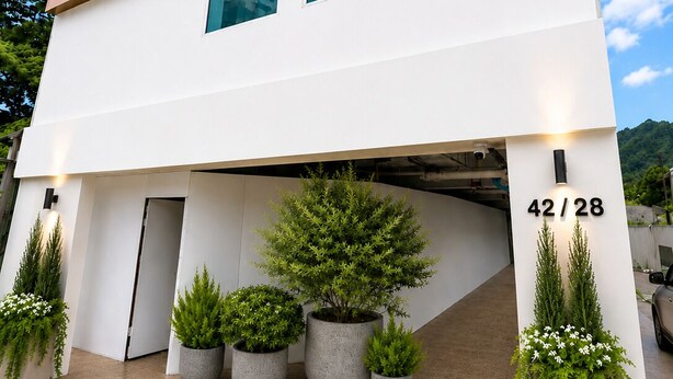Un edificio moderno con un letrero que dice 'SYAMA MANSION' y la entrada a un estacionamiento.