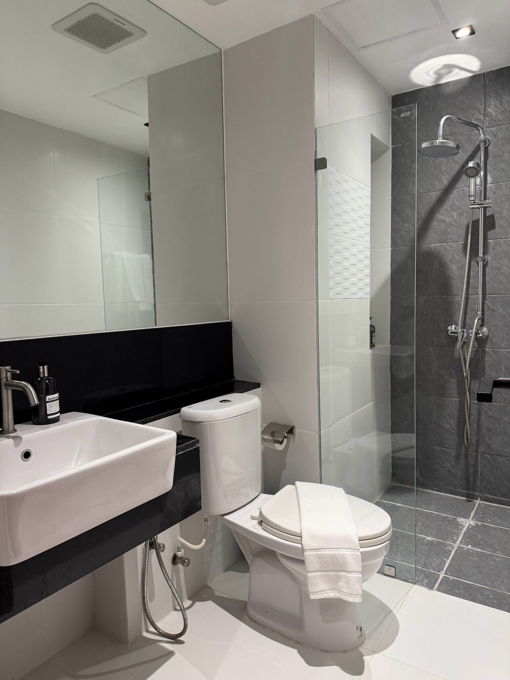 Un baño moderno con lavamanos, inodoro y ducha blancos.