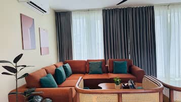 A modern living room with a sectional sofa, a rattan chair, and a ceiling fan.