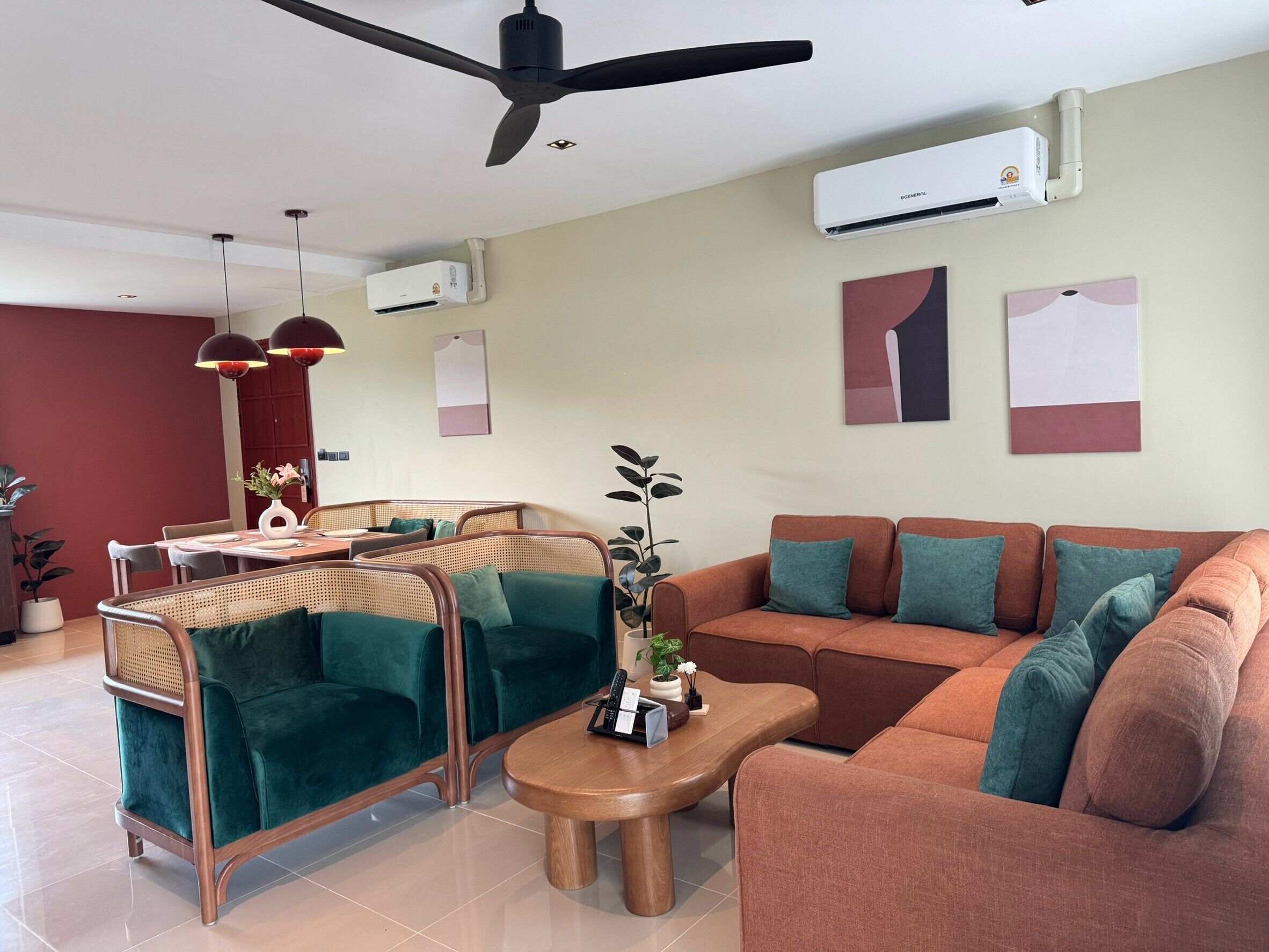 A modern living room with a ceiling fan, a dining area with a table and chairs, and a sofa with cushions.