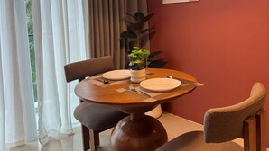 Un comedor con una mesa redonda, sillas, una planta en maceta y una lámpara colgante.