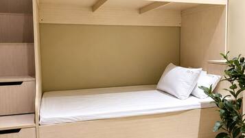 Una cama litera con cabecera de madera, un colchón y almohadas.