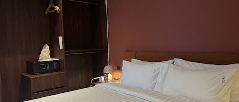 Une chambre d’hôtel équipée d’un lit, d’une armoire, d’une table de chevet avec une lampe et d’un téléphone fixé au mur.