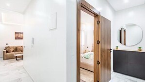 Une chambre à coucher moderne avec un lit, une armoire en bois, un miroir rond et une petite plante posée sur la commode.