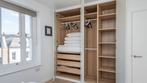 Une chambre avec un grand dressing, un lit et une fenêtre.