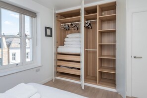 A bedroom with a large walk-in closet, a bed, and a window. - 1850s Victorian Flat, Terrace, Near Central London (Greater London)