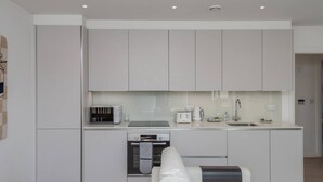 Une cuisine moderne avec des meubles blancs, un four encastré, un grille-pain et une machine à café.