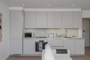 Eine moderne Küche mit weißen Schränken, einem Einbauofen, einem Toaster und einer Kaffeemaschine.
