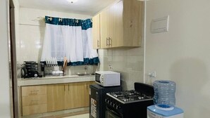 A kitchen with a gas stove, microwave, and water dispenser. - Soothing 1-bedroom apartment in vibrant Nairobi perfect for relaxing stay (Nairobi)