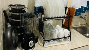A kitchen with a blender, stacked pots, a dish rack with glasses, and a wooden spoon. - Soothing 1-bedroom apartment in vibrant Nairobi perfect for relaxing stay (Nairobi)