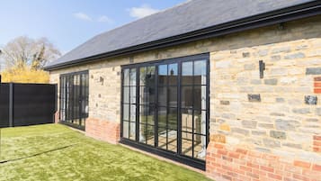 A stone building with large windows and a brick foundation.