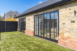 A stone building with large windows and a well-maintained lawn. - Converted Barn with Oak Beams near Cotswolds (Highworth)