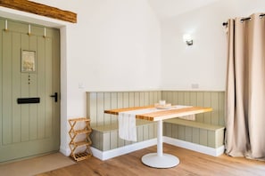 Ein Zimmer mit Holztisch, Bank, einer Tür mit Bild und einer Wandleuchte.