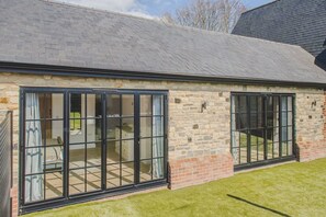 A building with large sliding glass doors, a brick exterior, and a sloped roof.