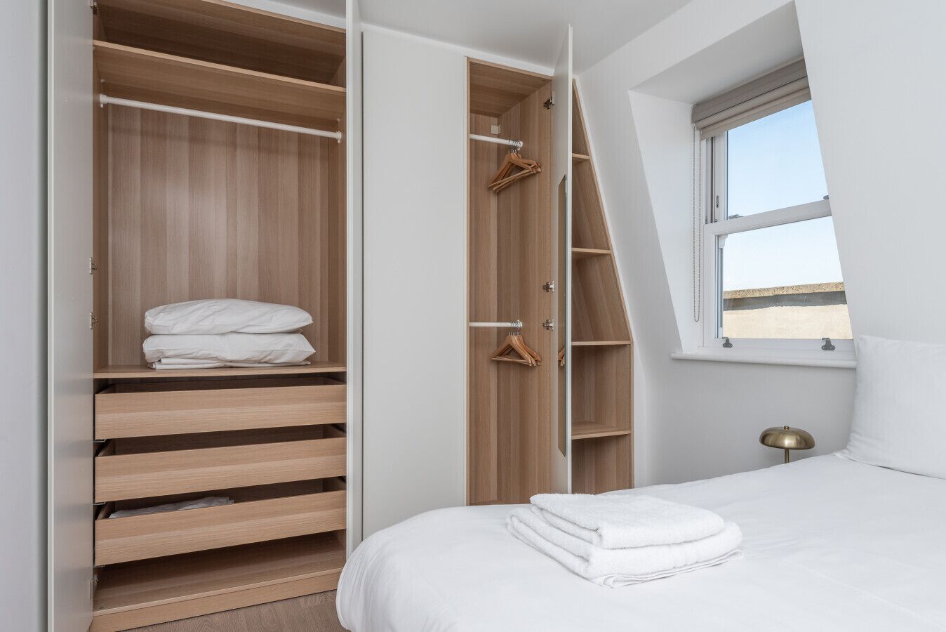 Un dormitorio con un armario amplio, una cama y una ventana con vistas.