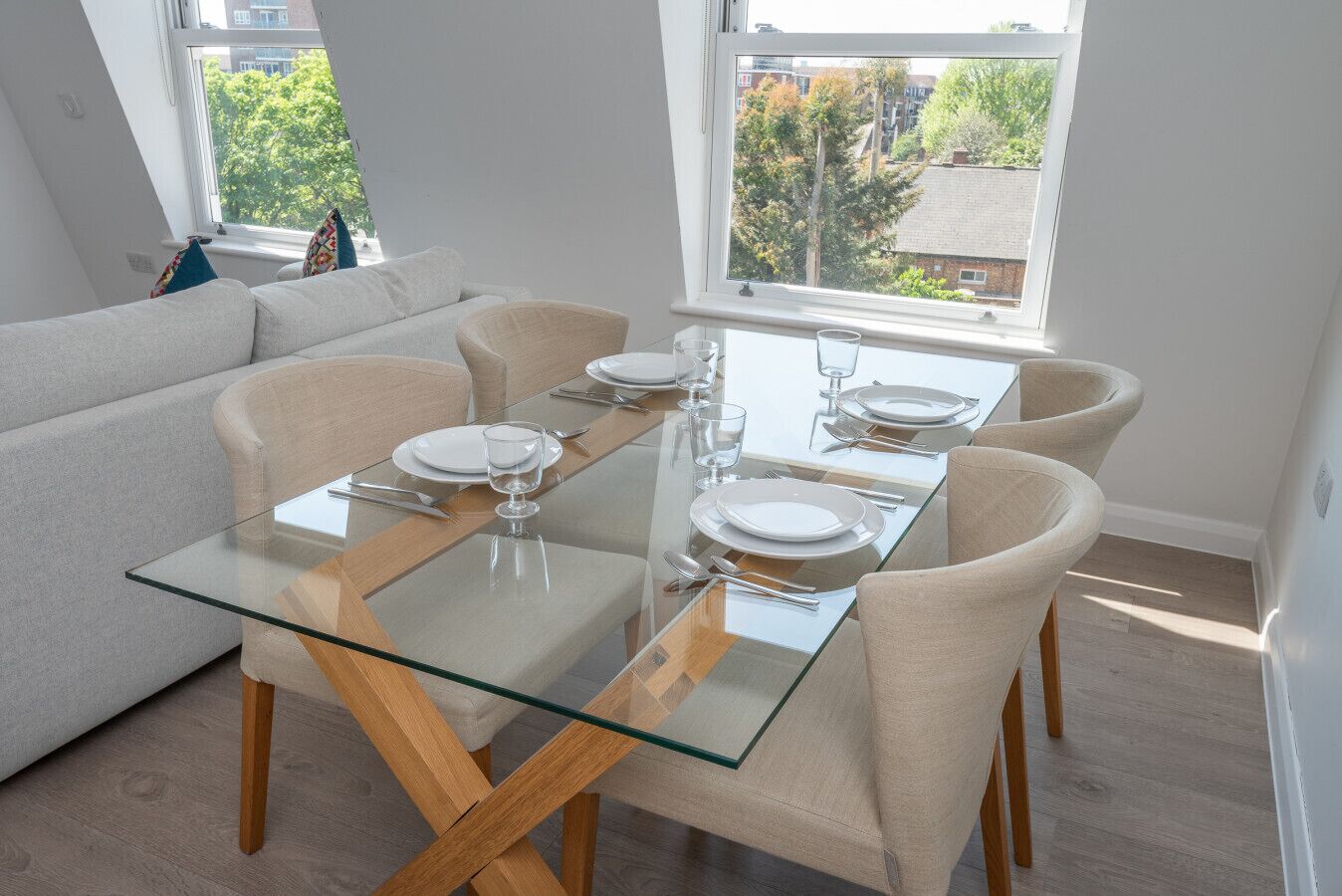 Un comedor moderno con una mesa de vidrio, cuatro sillas y un sofá.