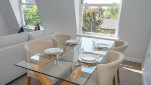 Un espace repas moderne avec une table en verre, quatre chaises et un canapé.
