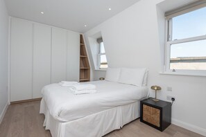 Ein Schlafzimmer mit Bett, Nachttisch, Kleiderschrank und einem Fenster mit Blick.