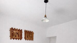 Et soveværelse med en seng, hvidt sengetøj, et træsengegærde, to billeder på væggen, et sengebord og en hængende lampe.