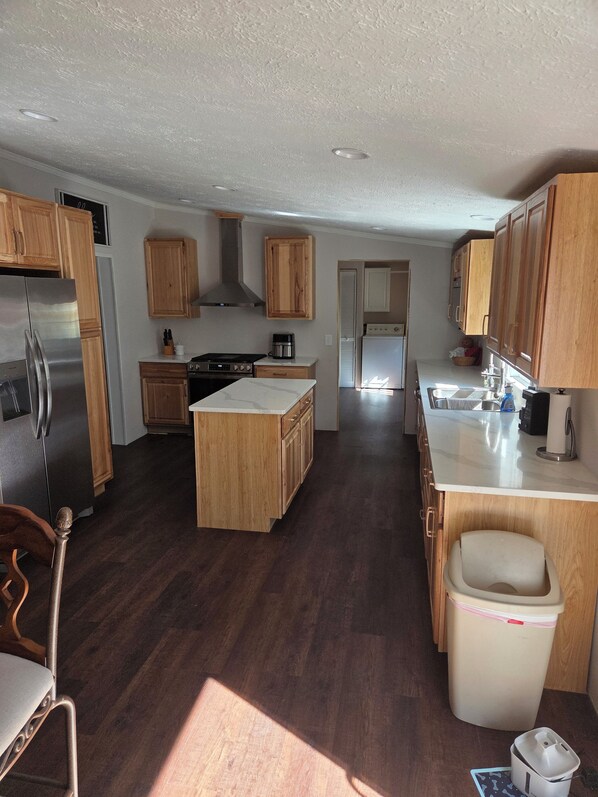 A kitchen with wooden cabinets, a stainless steel refrigerator, a stove, and a sink.