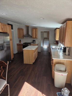 A kitchen with wooden cabinets, a stainless steel refrigerator, a stove, and a sink.