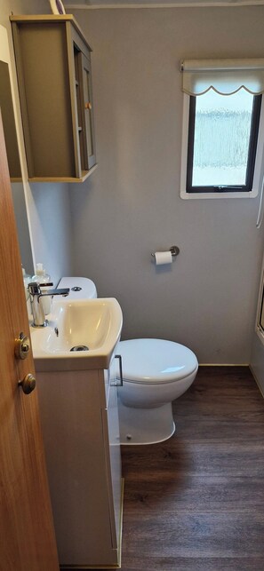 Un baño con inodoro, lavamanos y ventana.
