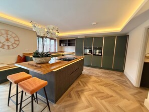 Eine moderne Küche mit Kochinsel, Holzboden und einer Uhr an der Wand.