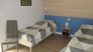 Une chambre avec deux lits, une chaise, une table de chevet et un tableau au mur.