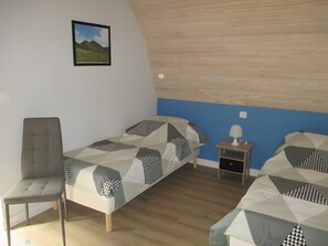 A bedroom with two beds, a chair, a nightstand, and a picture on the wall. - Gîte in the Heart of the Countryside with Private Garden (Avèze)