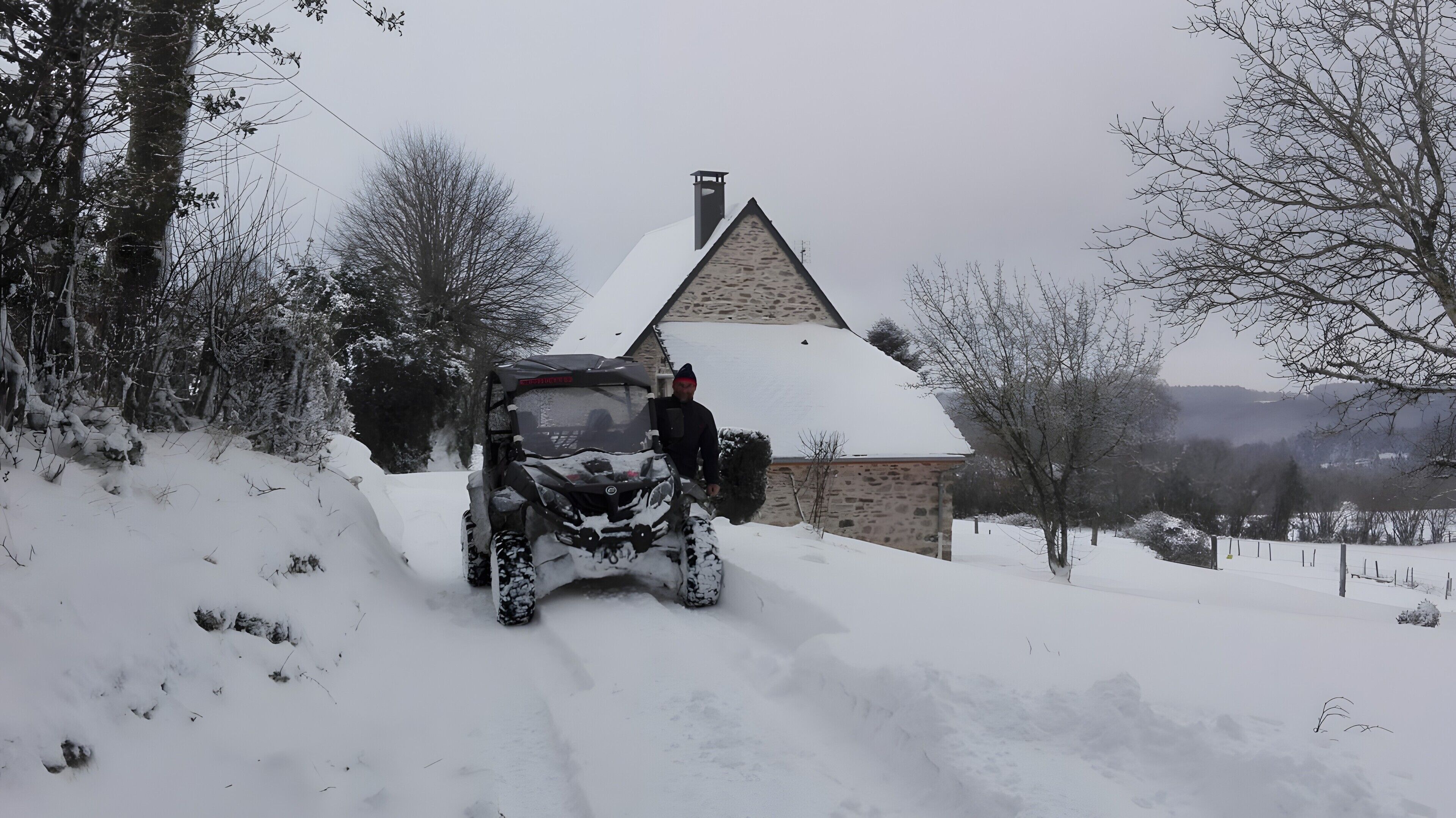 A snow-covered landscape with a stone building and a vehicle.