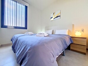 A bedroom with a bed, two bedside tables, a window, and a wall-mounted light fixture. - Ground Floor Apartment with Direct Pool Access (Mar de Cristal)