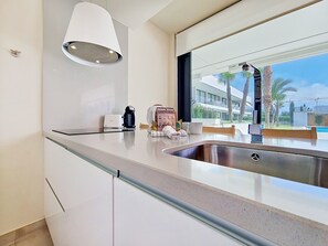A modern kitchen with a built-in sink, a coffee maker, and a welcome sign. - Ground Floor Apartment with Direct Pool Access (Mar de Cristal)