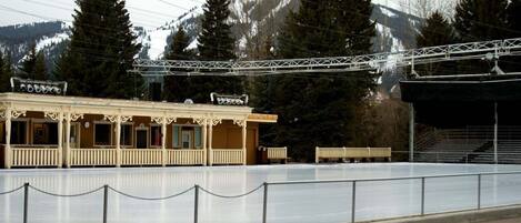A building with a balcony, a chain-link fence, and a mountainous backdrop.