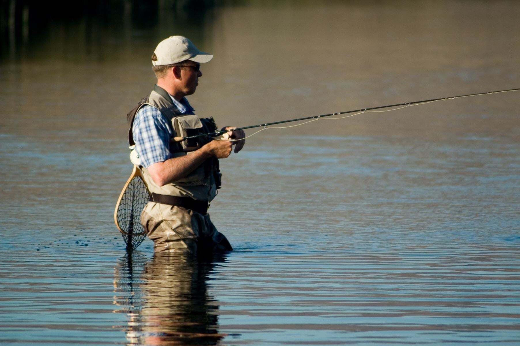 A person standing in water holding a fishing rod.