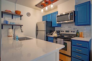 A modern kitchen with blue cabinets, stainless steel appliances, and a white countertop. - Stonehenge Condo #6 - Walk to River Run & Main Street (Ketchum)
