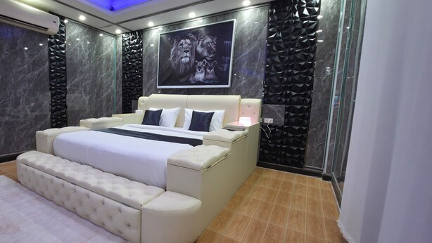 A modern bedroom with a large bed, a wall-mounted TV, and a marble wall. - Ventura Boutique Residence (Pattaya)