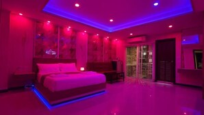 A bedroom with a bed, nightstands, and a sliding glass door leading to a balcony. - Ventura Boutique Residence (Pattaya)