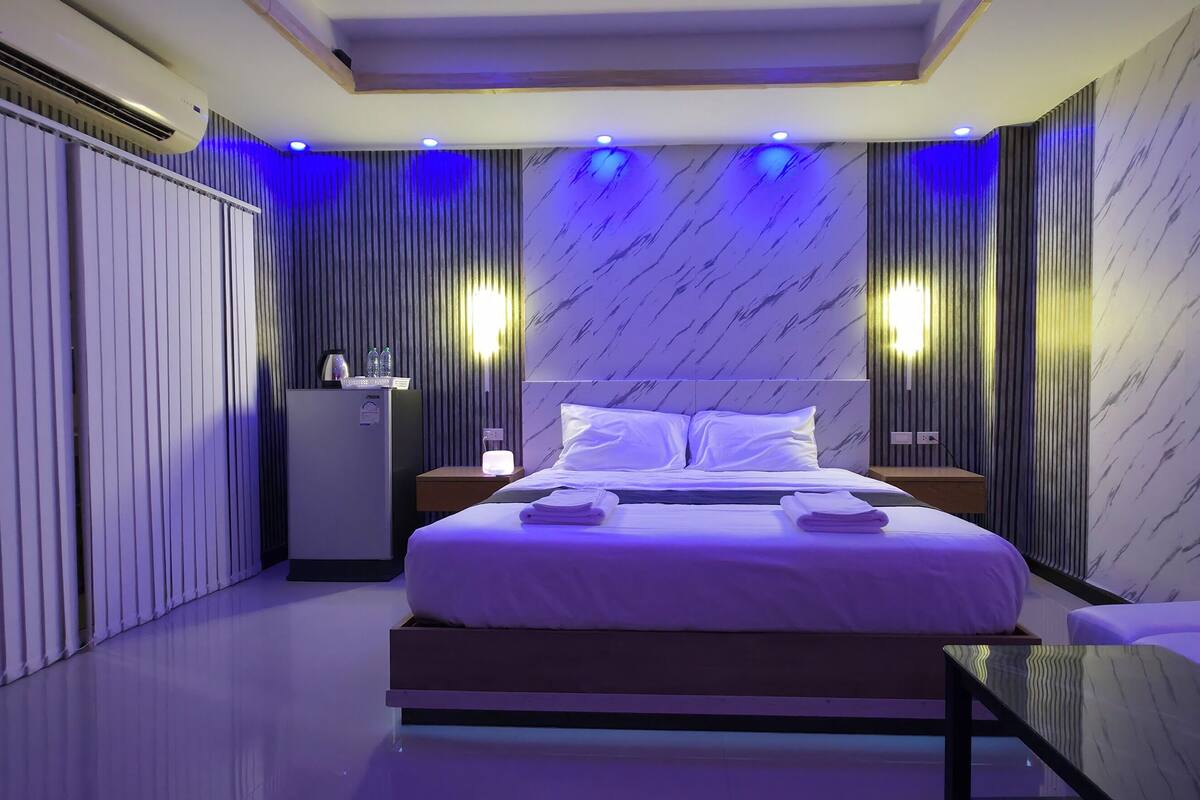 A modern bedroom with a bed, bedside tables, a wardrobe, and a seating area.