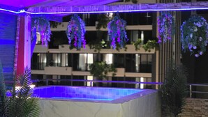 A rooftop pool area with hanging plants and a view of a building in the background. - Ventura Boutique Residence (Pattaya)