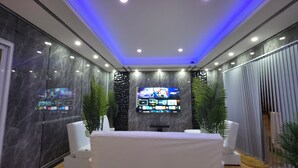 A modern room with a flat-screen TV, marble walls, and a ceiling with blue lighting. - Ventura Boutique Residence (Pattaya)