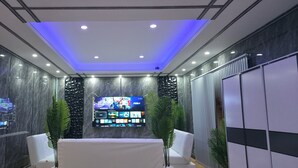 A modern room with a flat-screen TV, a table, two chairs, and a decorative wall panel. - Ventura Boutique Residence (Pattaya)