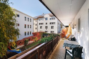 Un balcón con mesa y sillas, un tobogán y un jardín con plantas de colores.