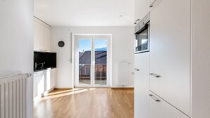 Una cocina moderna con armarios blancos, encimera negra y vistas a un balcón a través de un ventanal.