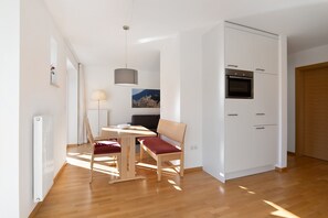 Eine moderne Küche mit weißen Schränken, einem eingebauten Backofen und einem Essbereich mit Tisch und Stühlen.