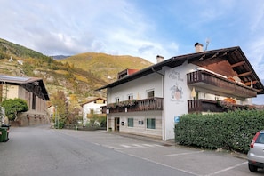 Ein Gebäude mit Balkon, einem Schild mit der Aufschrift 'Gasthof' und einer Bergkulisse.