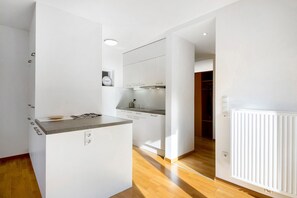Una cocina moderna con armarios blancos, una encimera y un horno empotrado.