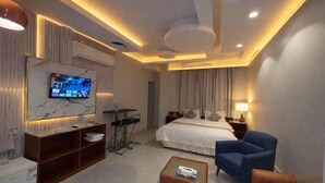 Una habitación de hotel moderna con una cama, un escritorio, un televisor y un espacio de descanso.