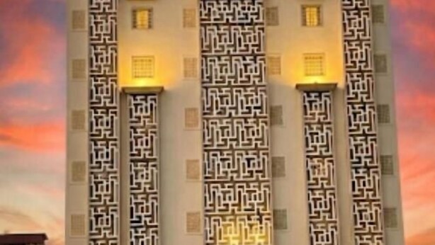 Un hotel con fachada moderna, varios balcones e iluminación de señalización.
