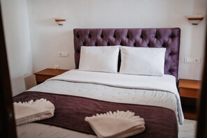 Una cama bien hecha con un cabecero capitonado, almohadas blancas y una manta marrón.