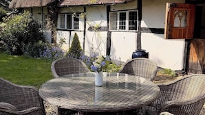 Een huis met rieten dak, een tuin en rieten meubels.
